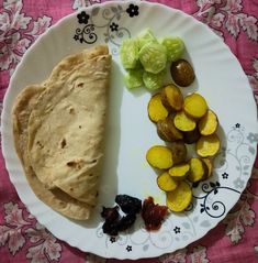 a white plate topped with food on top of a floral table cloth covered tablecloth