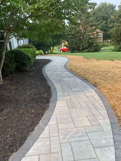 a brick walkway in the middle of a grassy area with trees and bushes on either side