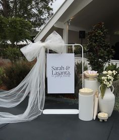 a white sign sitting on top of a table next to vases