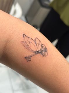 a small dragonfly tattoo on the arm