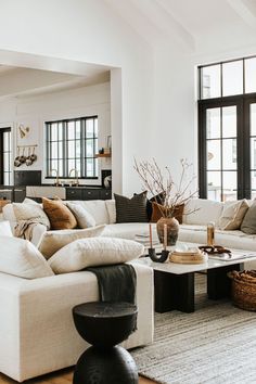 a living room filled with white furniture and lots of pillows on top of the couches