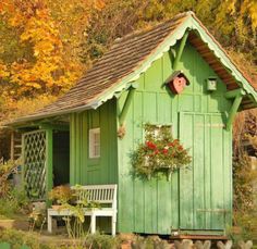 a small green shed with a potted plant in the window