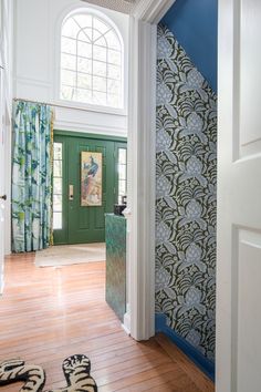 an open door leading into a room with blue and green wallpaper