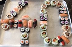 a metal tray topped with lots of different types of sushi