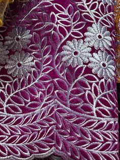 purple and gold embroidered fabric with white flowers on the top, in front of a black background