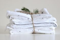 stack of folded white towels with black stripes and pine branch on top, stacked in front of each other