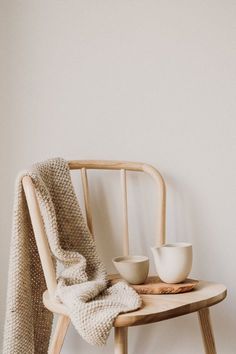 a wooden chair sitting next to a white bowl and cup on top of a table