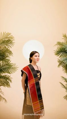 a woman standing in front of palm trees wearing a red, black and gold sari