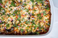 a white casserole dish filled with lots of toppings and veggies