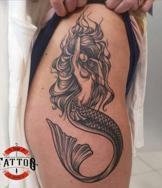 a woman's thigh with a mermaid tattoo on it