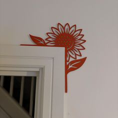 a red metal flower on the side of a white door