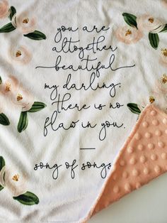 a handwritten quote on a white towel with pink flowers