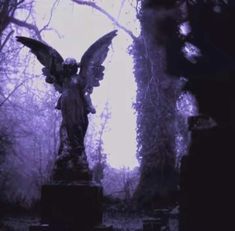 an angel statue in the middle of a cemetery with purple lighting on it's wings