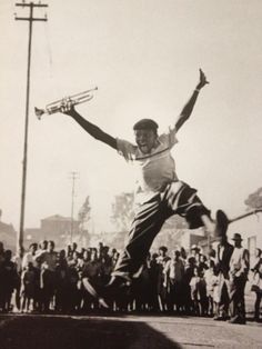 a man jumping in the air with a tennis racquet on his hand while people watch