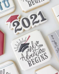 cookies decorated with graduation decorations and the words 2021 are displayed on a white tablecloth