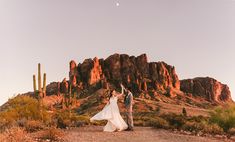 a bride and groom standing in the desert