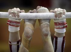 the legs and feet of a person on a bar with their hands in the air