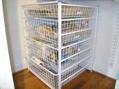 a white wire storage rack filled with lots of food and drinks on top of a hard wood floor