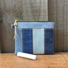 a blue and white striped denim pouch with a remote control in front of it on a wooden surface