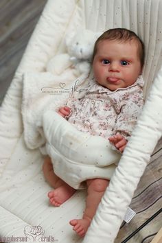 a baby sitting in a white chair with a teddy bear on it's back