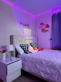 a bed room with a neatly made bed and purple lights on the ceiling above it