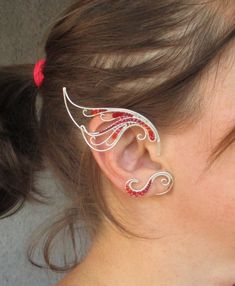 a close up of a person wearing some kind of ear cuff with red and white designs on it