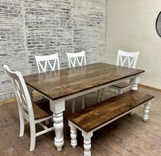 a dining table with four chairs and a bench in front of a white brick wall