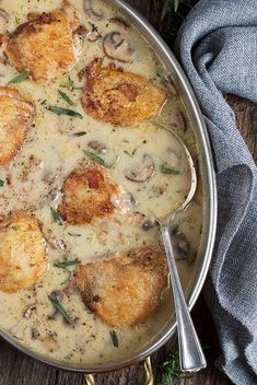 a pan filled with chicken and mushrooms covered in gravy on top of a wooden table