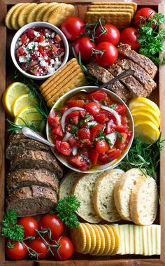 a wooden tray filled with different types of food and crackers on top of it