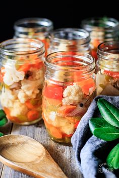 several jars filled with food sitting on top of a wooden table next to a spoon