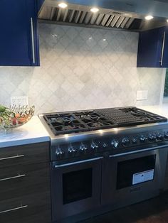 a stove top oven sitting inside of a kitchen next to blue cupboards and drawers