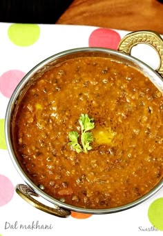 a metal bowl filled with food sitting on top of a polka dot tablecloth covered table