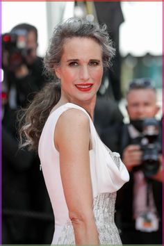 a woman with grey hair wearing a white dress and red lipstick on the red carpet