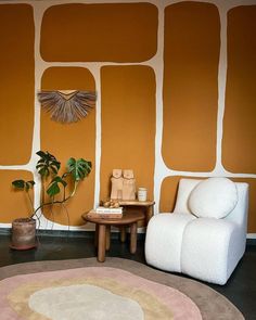 a living room with an orange wall and white chair next to a small coffee table