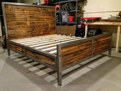 a bed frame made out of wood and metal in a room with workbench