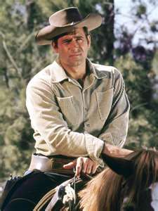 a man riding on the back of a brown horse wearing a cowboy's hat