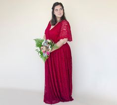 a woman in a red dress is holding a bouquet and posing for the camera with her hands on her hips