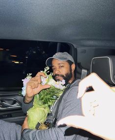 a man sitting in the back seat of a car holding flowers