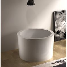 a white bath tub sitting on top of a hard wood floor next to a painting