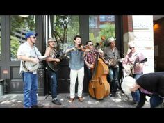 a group of people standing around each other with guitars in front of a storefront