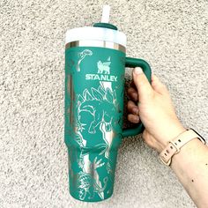 a hand holding a green starbucks cup on top of a carpeted floor next to a person's arm