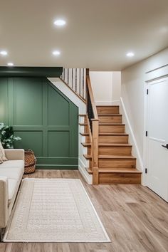 a living room filled with furniture next to a stair case and wooden floored stairs