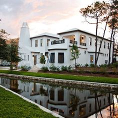 a large white house sitting next to a small lake in front of it's reflection