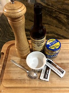 a wooden tray with spoons, salt and pepper shakers next to an empty bottle