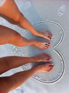 two women's bare feet standing in the snow