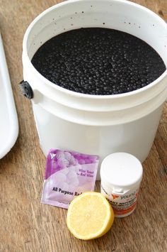 a bucket filled with black liquid next to a lemon slice and some other items on a wooden table