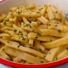 a red and white bowl filled with macaroni and cheese covered in parsley