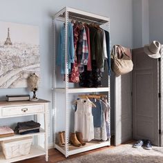 an organized closet with clothes, shoes and handbags hanging on the rack in front of a painting