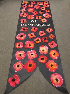 a black banner with red and orange flowers on it that says, we are remember