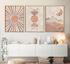 three paintings are hanging on the wall above a white cabinet in a modern living room